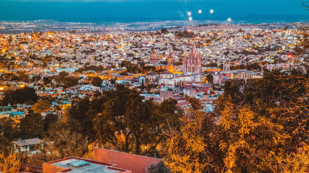 A stunning aerial view of San Miguel de Allende lit up at night, highlighting its iconic churches and vibrant streets among the safest cities in mexico