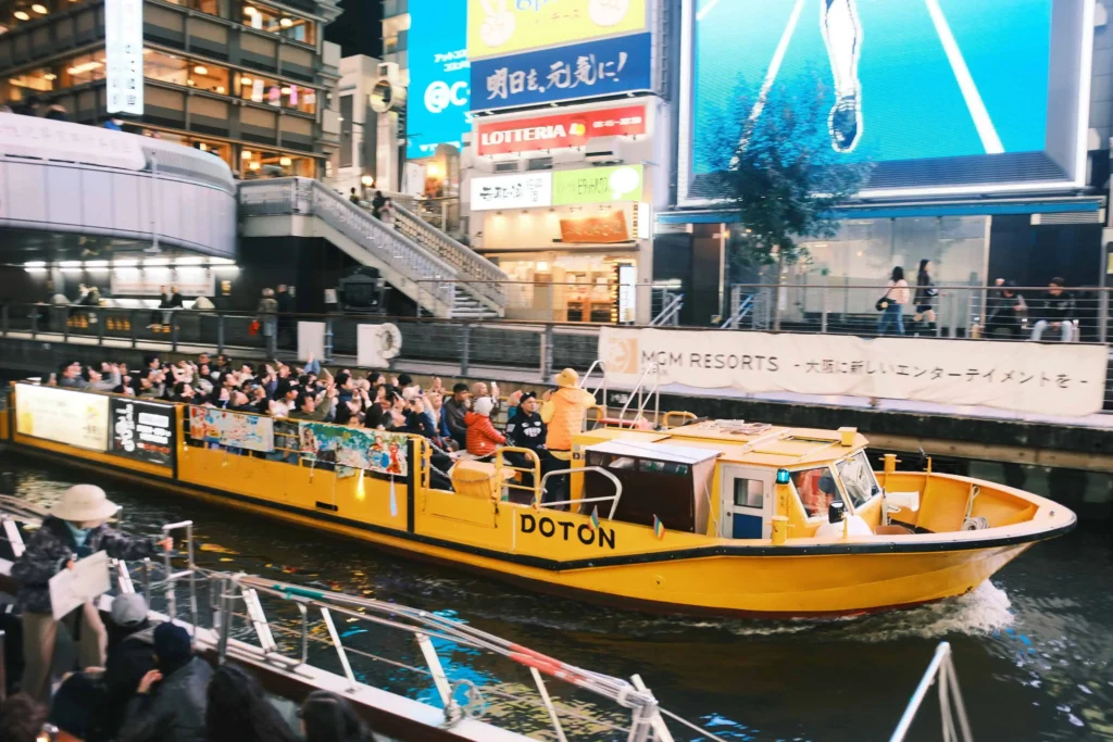 A brightly lit boat cruising on the Dotonbori River in Osaka to do include in japan itinerary 14 days