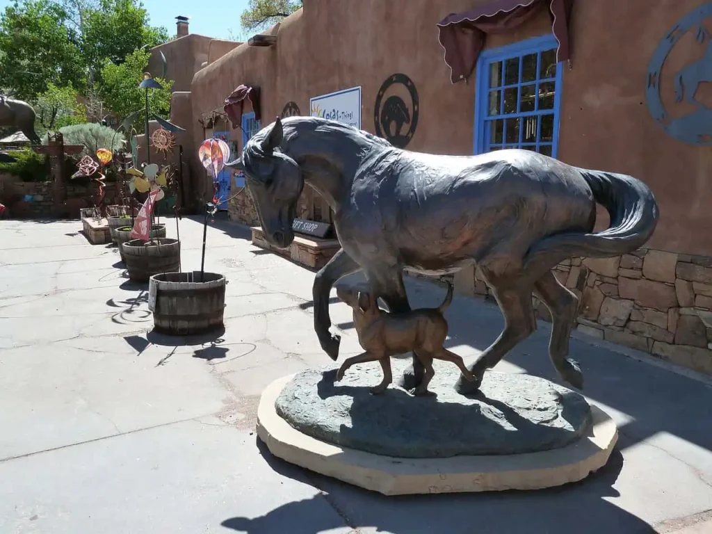 A bronze horse sculpture with artistic decor outside a shop in Santa Fe.