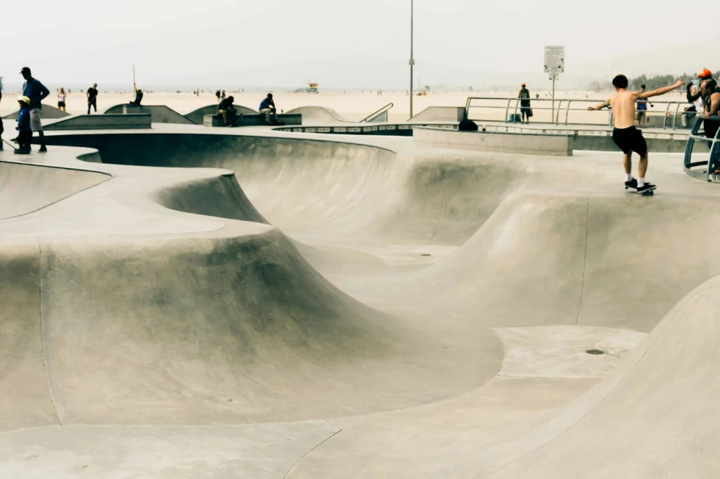 Skaters enjoying the Venice Beach skatepark, surrounded by sandy beaches and a sunny California sky.