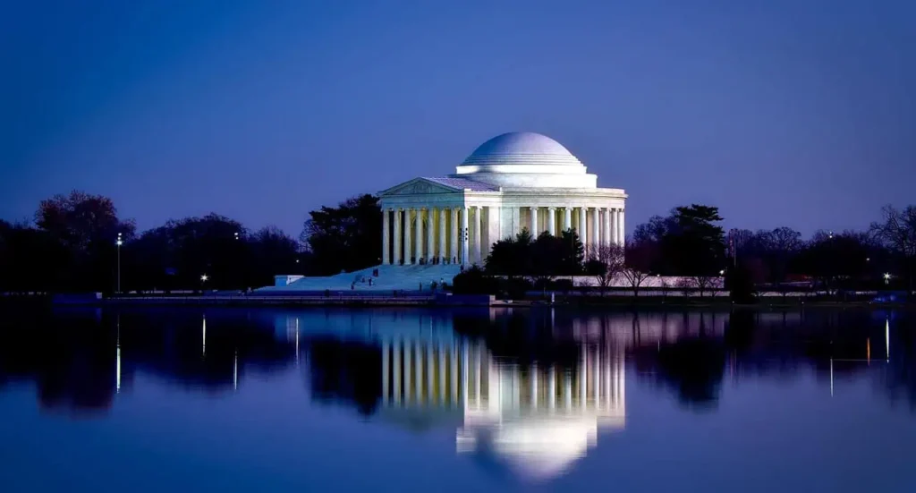 Illuminated Jefferson Memorial reflecting in the water at night in Washington DC.