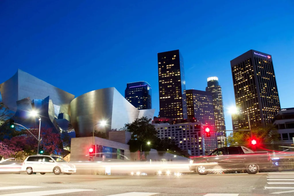 A stunning night view of the Los Angeles skyline with iconic buildings illuminated under a clear blue sky.