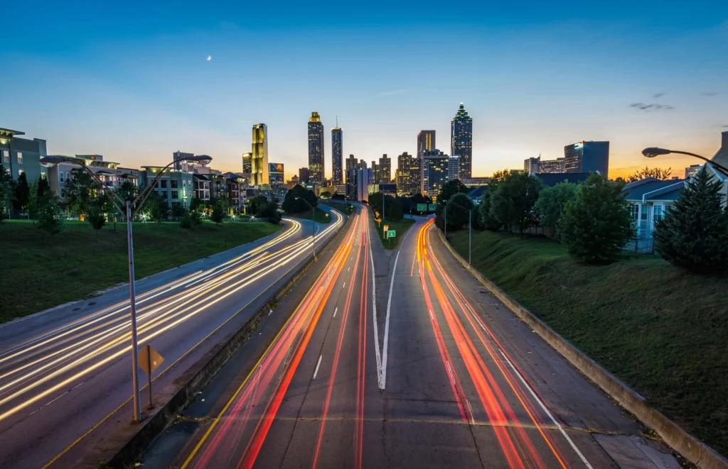 The Atlanta skyline captured from Jackson Street Bridge during twilight with vibrant light trails.
