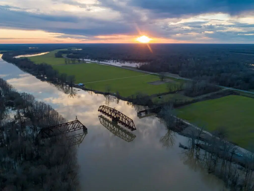 Sunset reflecting over the Yazoo River with a historic bridge in the foreground.