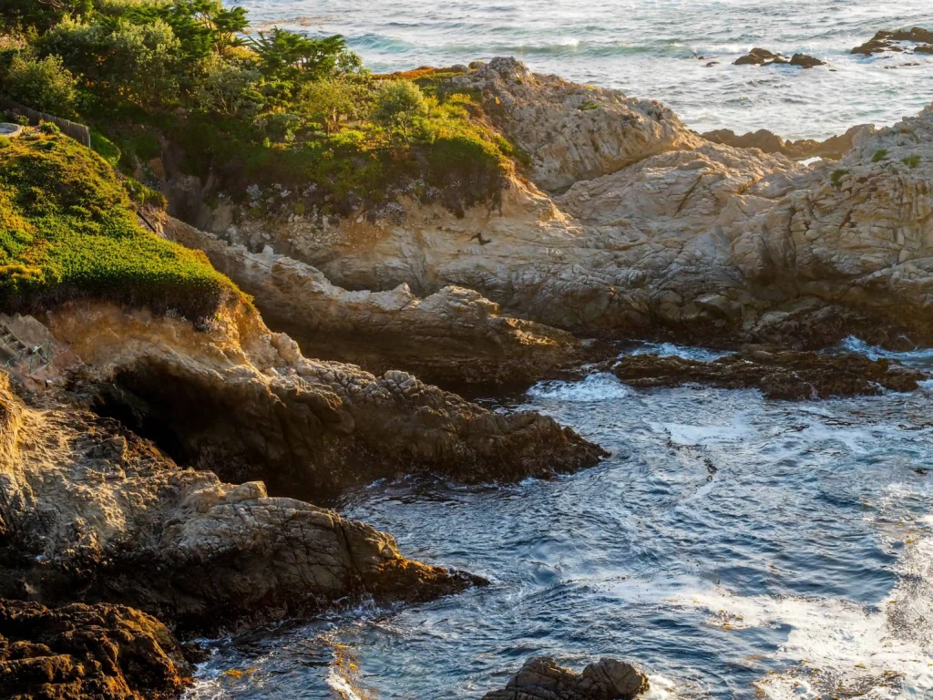 Rocky cliffs adorned with lush greenery overlooking the Pacific Ocean at Carmel Point.