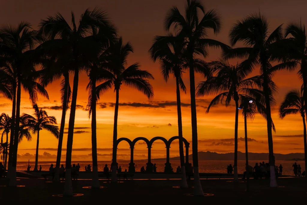 A silhouette of palm trees and arches at sunset on the Malecón in Puerto Vallarta, one of the safest cities in mexico