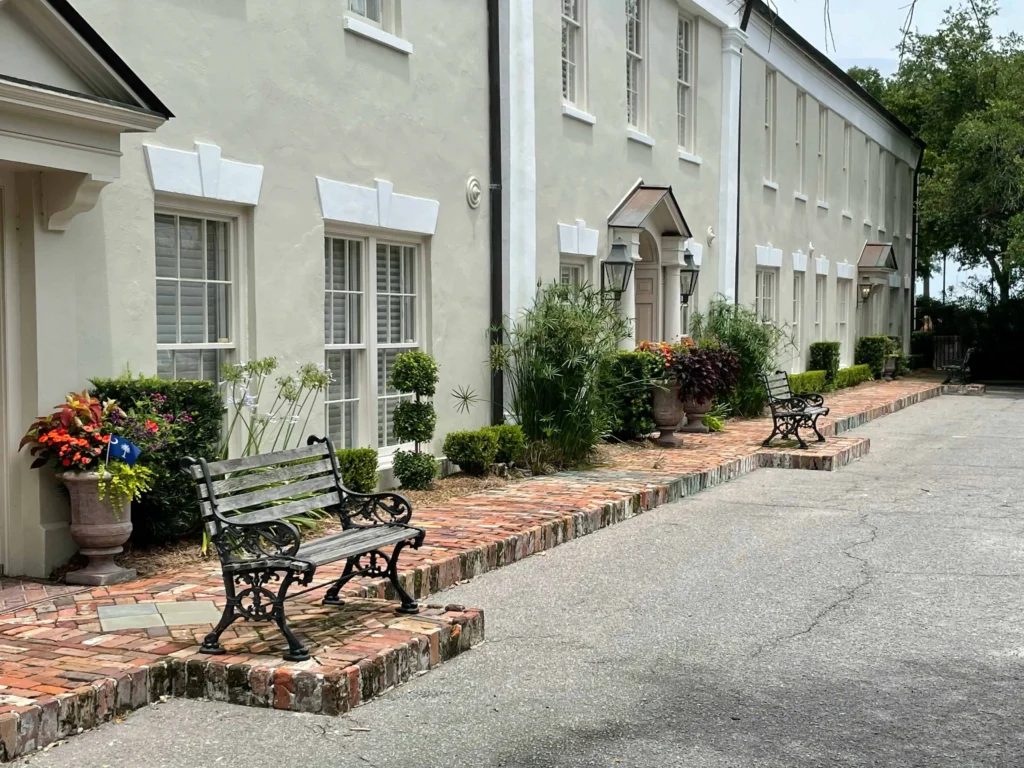 A serene brick walkway lined with benches and greenery near historic buildings in Charleston, SC.