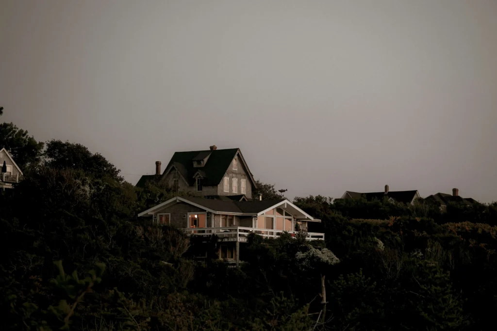 Scenic view of cliffside homes in Nantucket during twilight with glowing windows.