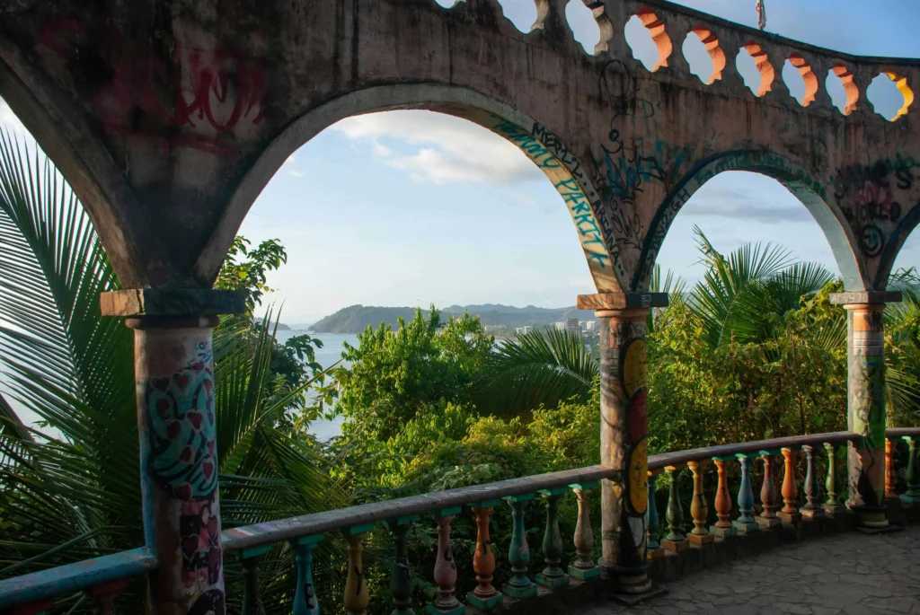 A scenic view of the ocean and forest framed by graffiti-covered arches at Miro’s Mountain in Jaco, Costa Rica.