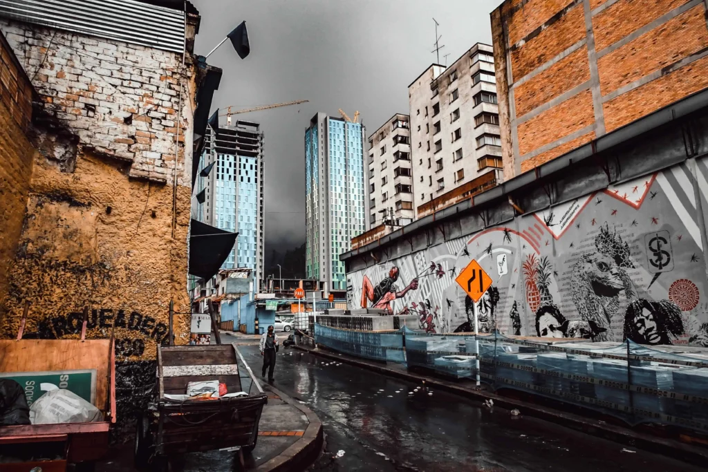 Street view of Bogota featuring urban graffiti and modern buildings under a cloudy sky.