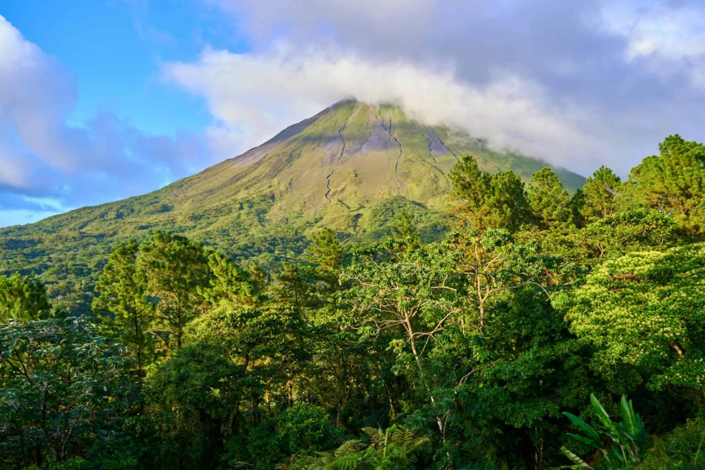 The majestic Arenal Volcano surrounded by lush greenery under a clear blue sky in La Fortuna, Costa Rica