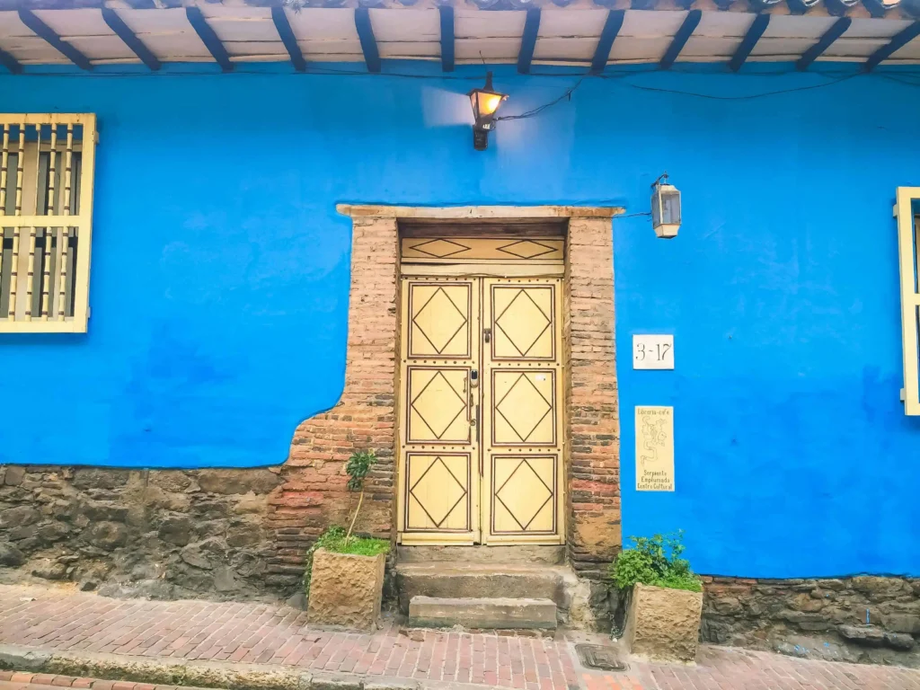 A vibrant blue colonial building with a yellow door in Bogota's historic district.