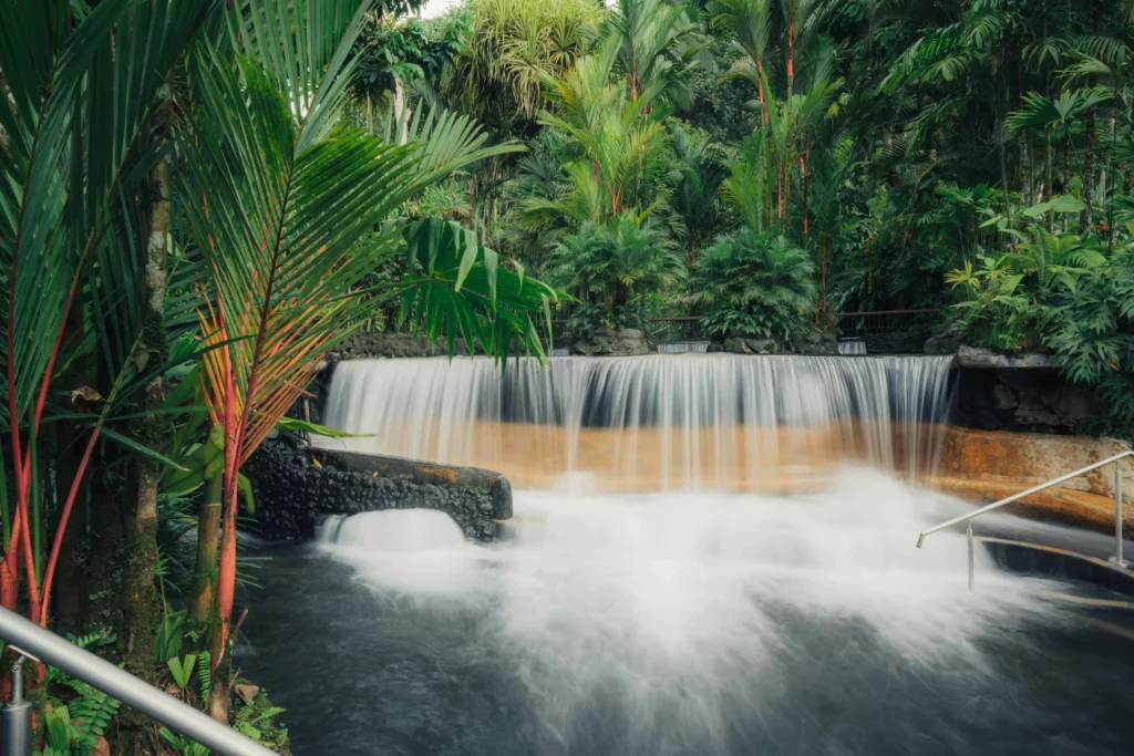 Relaxing hot springs surrounded by tropical plants and cascading waterfalls in La Fortuna, Costa Rica.