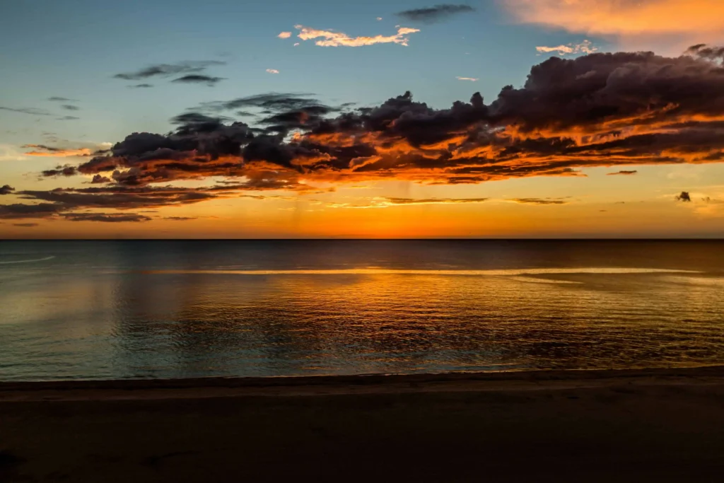 A stunning sunset over the calm ocean waters and sandy beach of Marco Island, Florida.