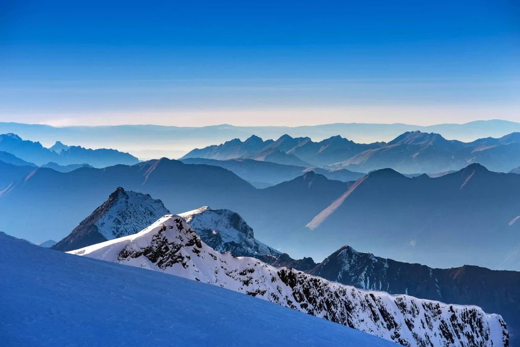 Snow-covered peaks of the Swiss Alps under a bright blue sky.