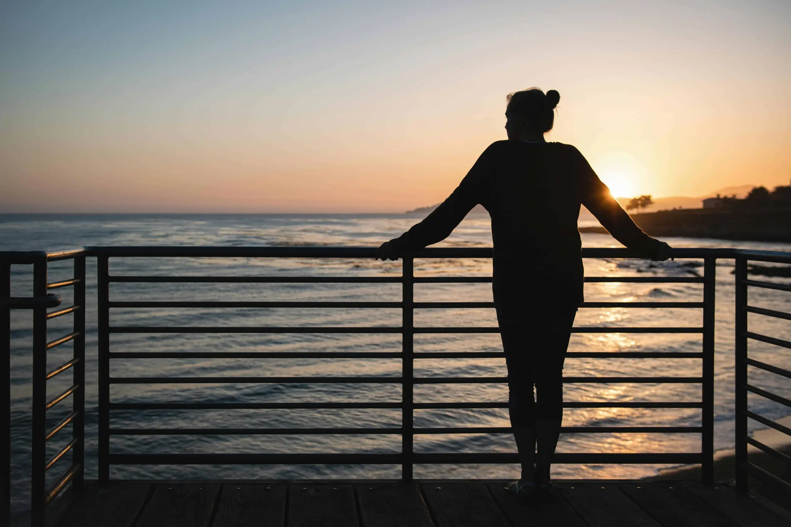 A silhouette of a woman enjoying the sunset from the Pismo Beach pier.