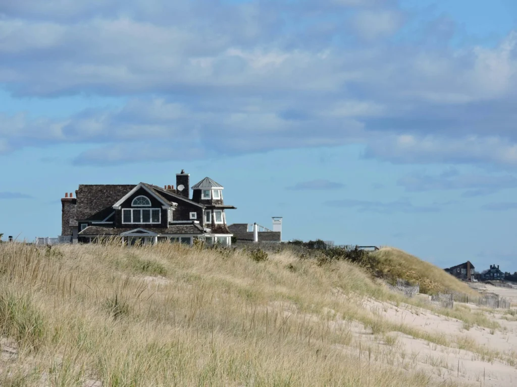 A quaint house overlooking sandy dunes and grass, with the ocean in the distance as one of the best weekend trips from nyc