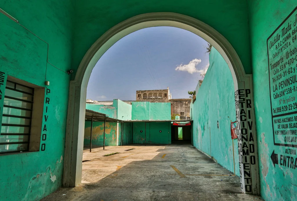 A view of a vibrant turquoise building and archway in Mérida, Mexico, showcasing colonial architecture.