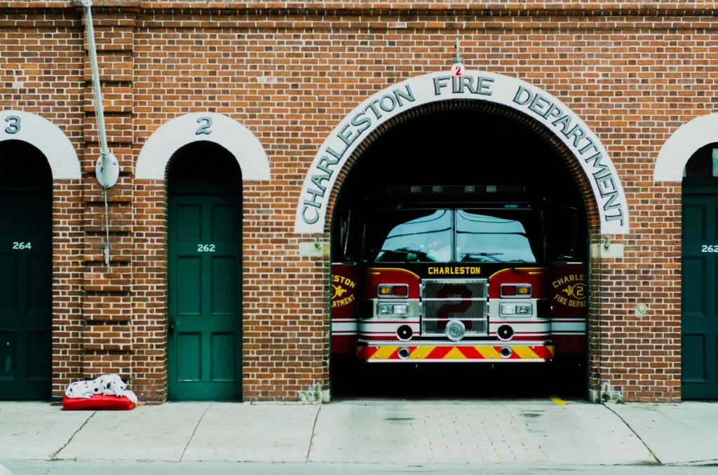 The Charleston Fire Department with a fire truck parked inside and red brick architecture.