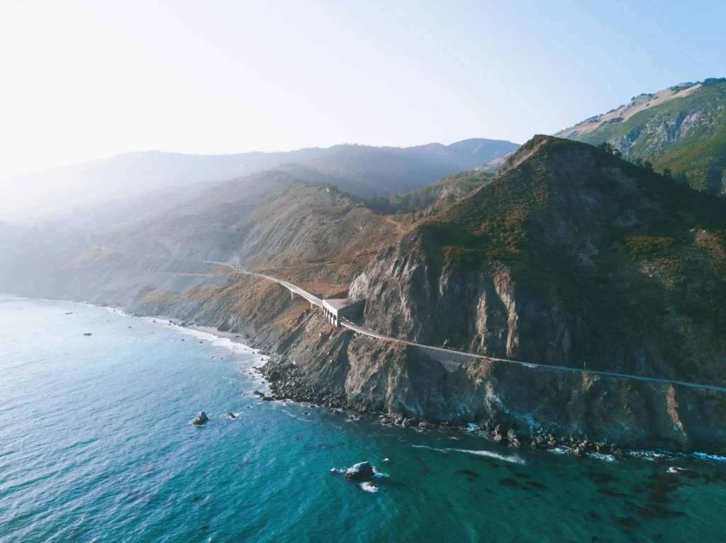 The Pacific Ocean and Big Sur coastline with scenic cliffs and crashing waves.