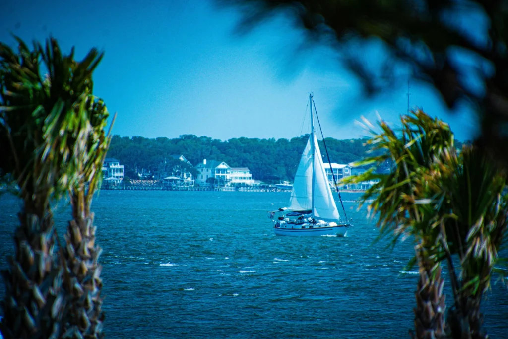 A sailboat cruising through the ocean with a scenic backdrop in Oak Island, NC.
