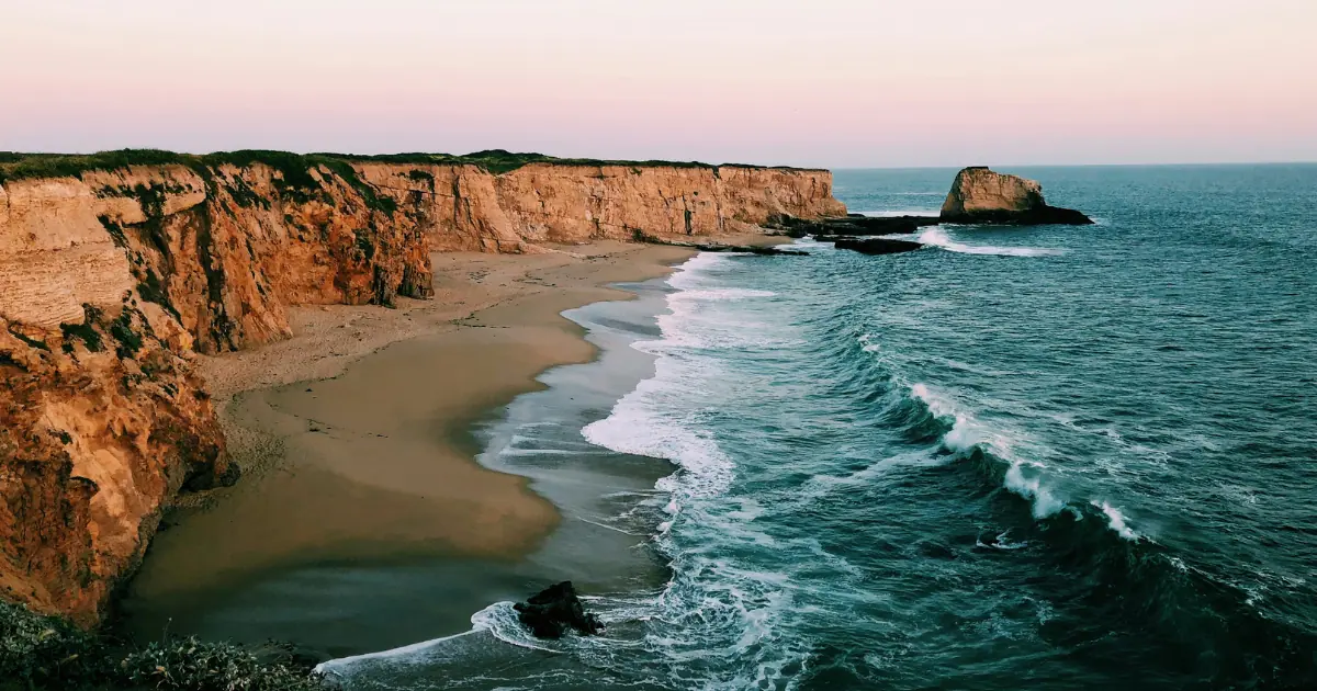 Scenic coastal cliffs and ocean waves in Santa Cruz at sunset.