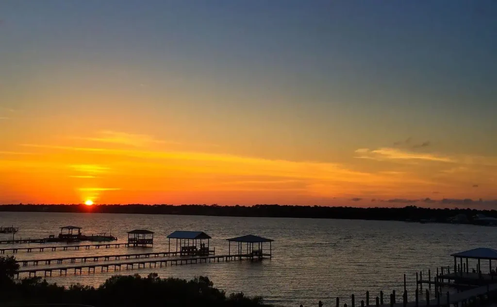 A sunset view over Orange Beach’s piers, reflecting golden hues on the water.