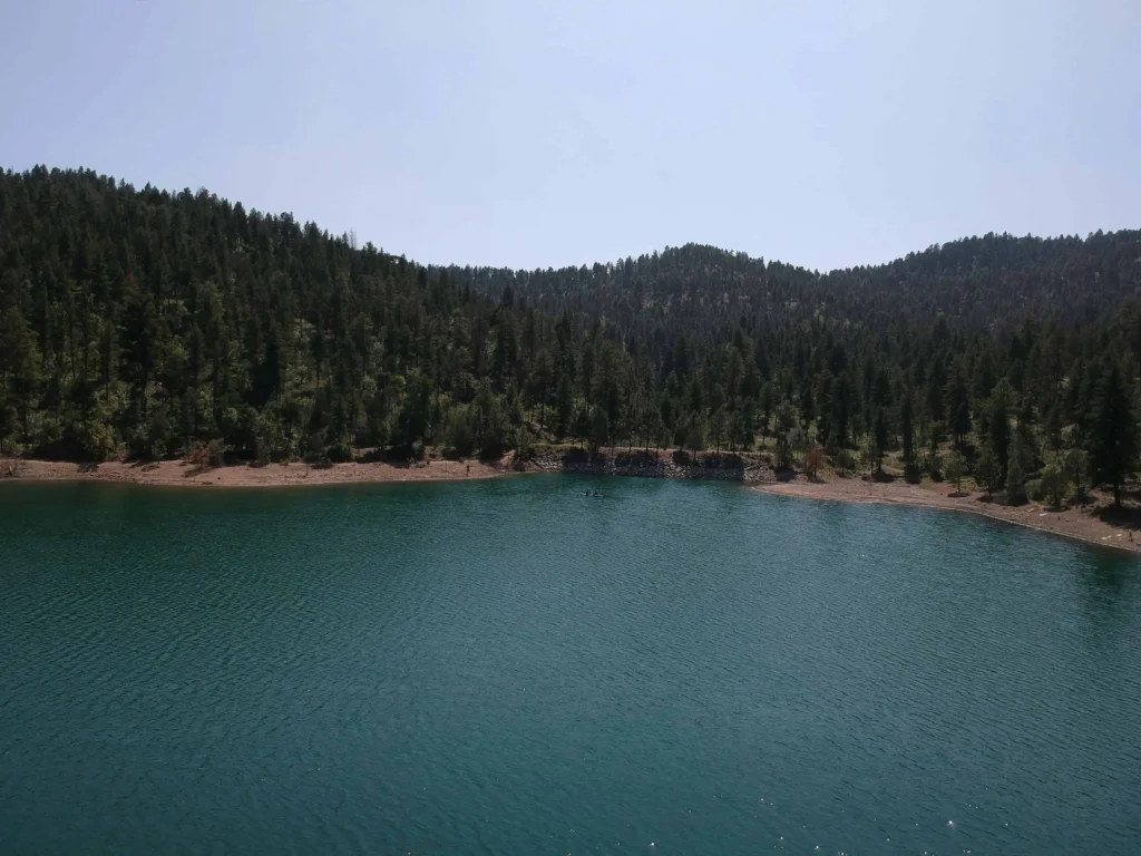 A peaceful lake surrounded by lush greenery and hills in Ruidoso, New Mexico.